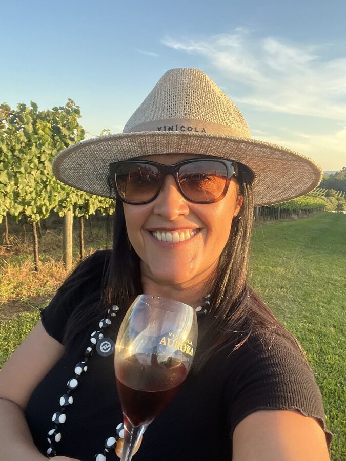 Mulher segurando taça de vinho durante pôr do sol nos vinhedos