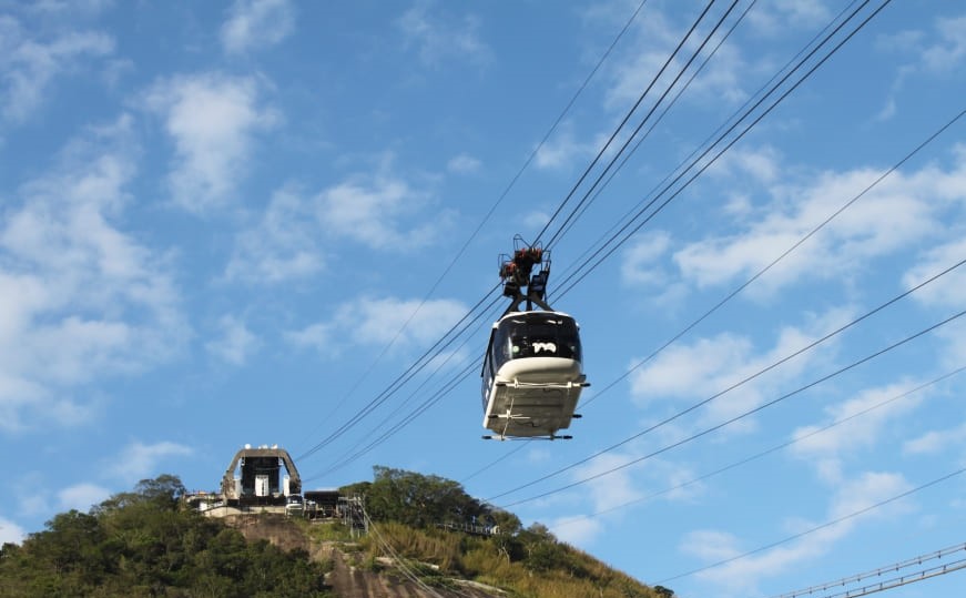 Sugarloaf cable car ascending toward the summit with blue skies in Rio de Janeiro.